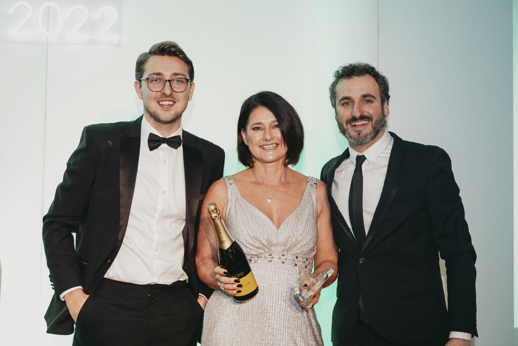 Three people, one of which is the Managing Director at Flame UK, posing for a photo with an award.