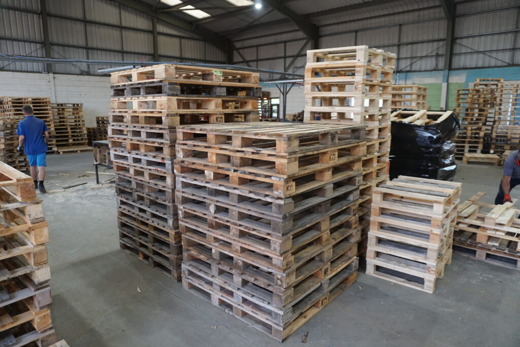 Recycled pallets stacked up inside a warehouse used to recycle pallets