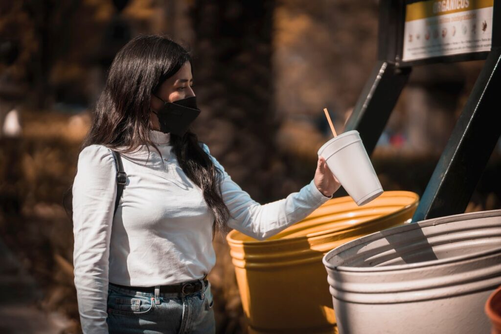 A woman choosing to recycle more by placing her rubbish in the correct bin