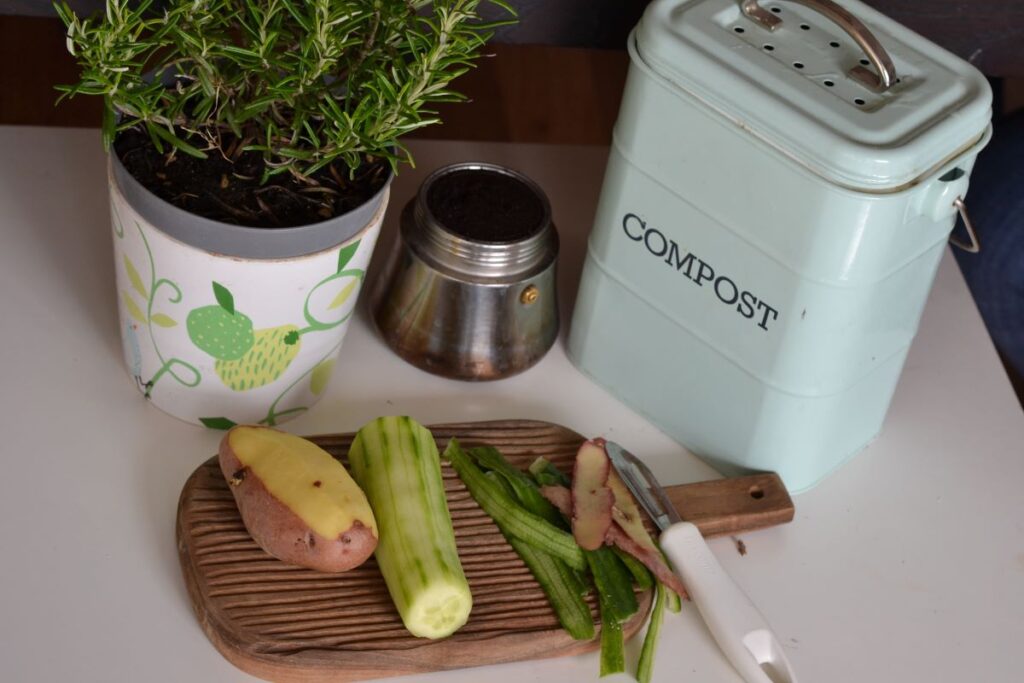 A compost bin on a counter with food scraps on a cutting board, a way for people to recycle more