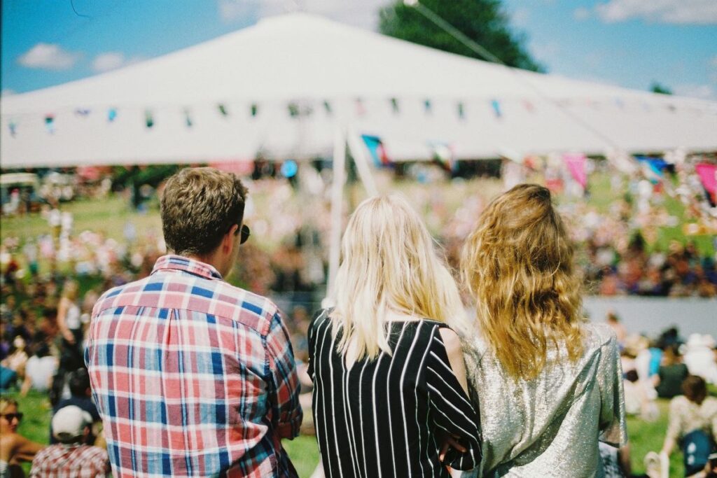 Three people with their backs to the camera at a festival