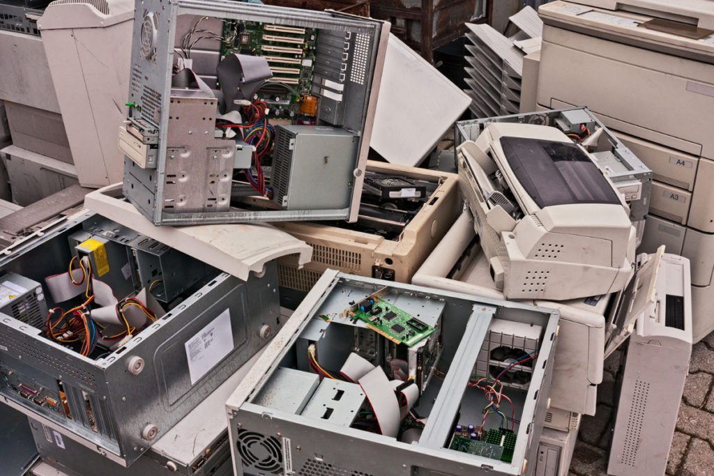 Lots of computer and electrical waste stacked on top of each other in a pile.
