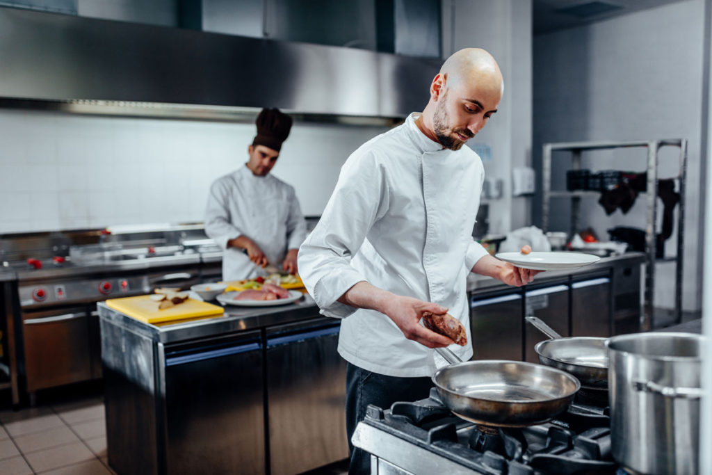 Two people in a restaurant kitchen cooking