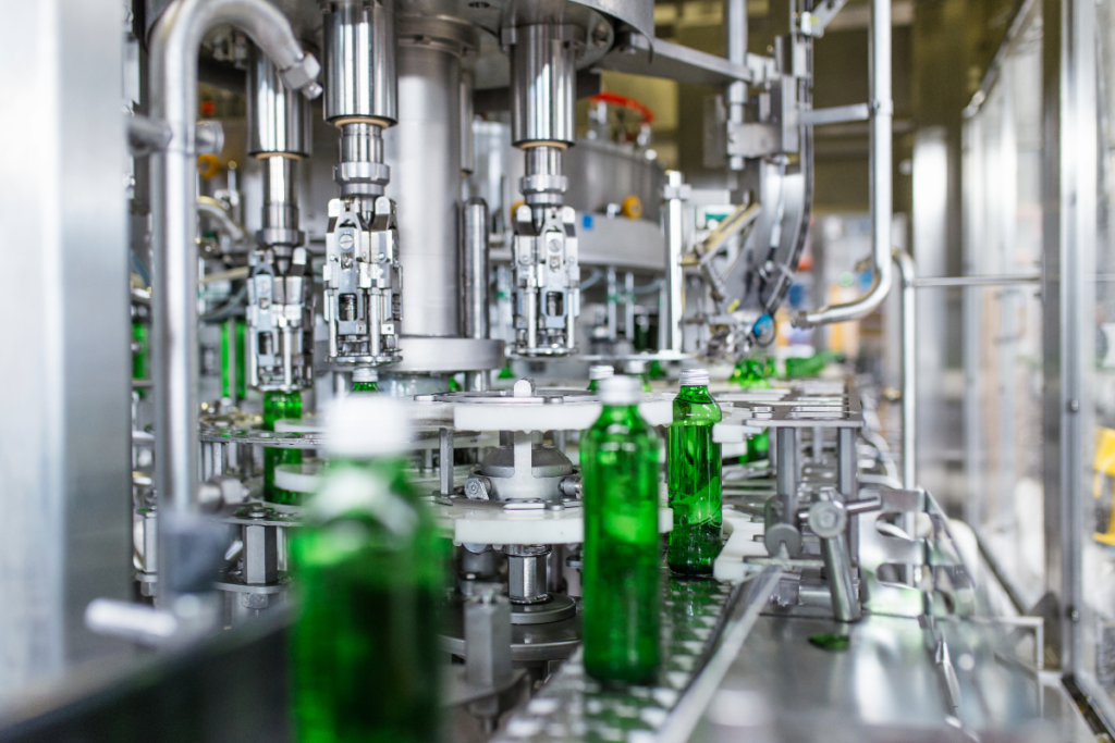 Green glass bottles in a production line machine at a factory